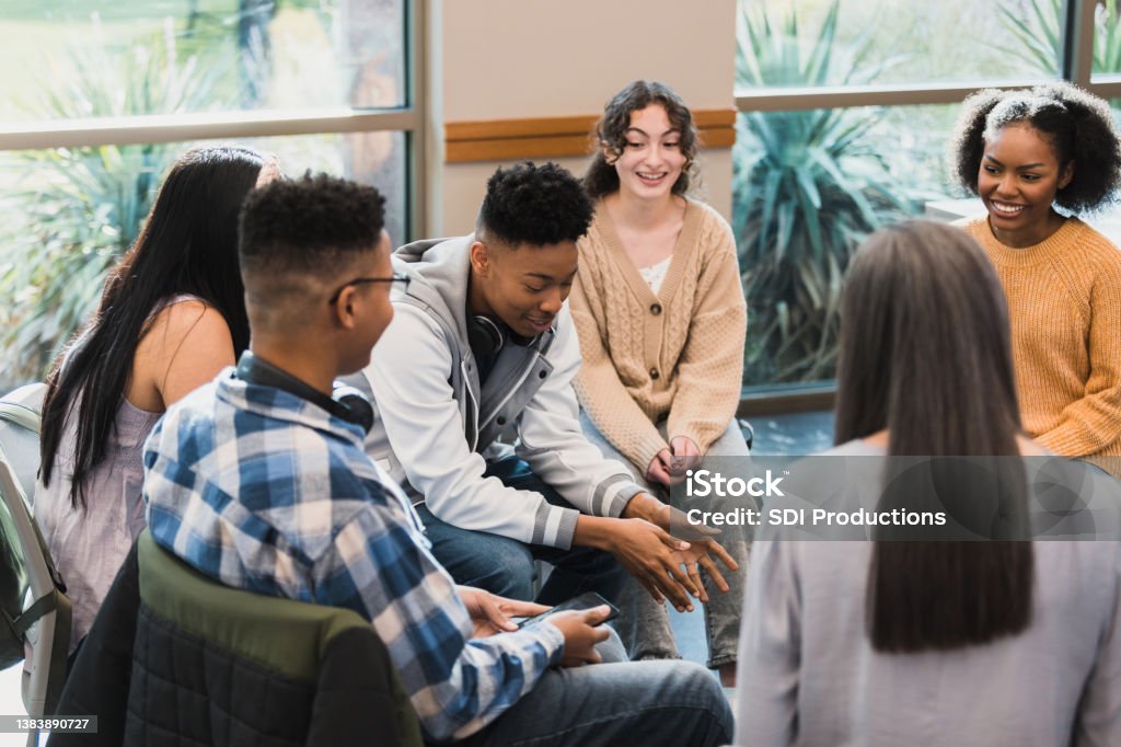 Young man is honest The group of peers listen proudly as their friend talks about a difficult time in his life. Teenager Stock Photo
