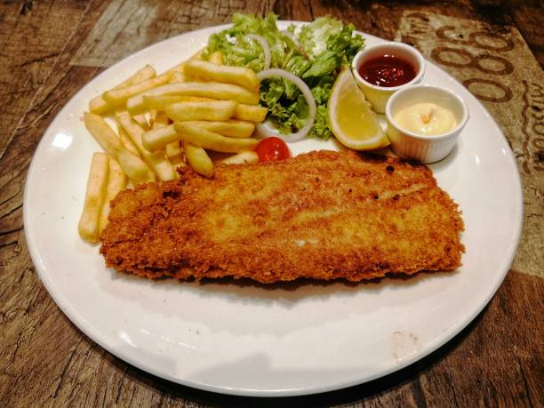 pescado y patatas fritas con ensalada, patatas fritas, limón, mayonesa y salsa de tomate en un plato. enfoque selectivo en un trozo de pescado. - fish cutlet fotografías e imágenes de stock