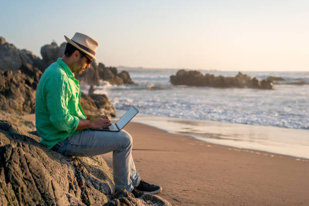 istock man sitting with a laptop alone at the beach 1383895958