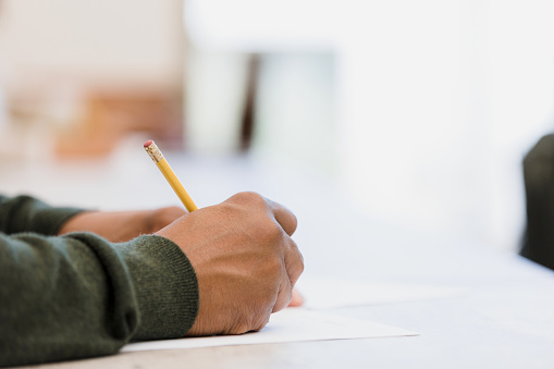 The unrecognizable person writes on his paper during class.