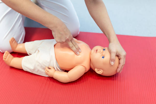 istock Woman performing CPR on baby training doll with one hand compression. First Aid Training - Cardiopulmonary resuscitation. First aid course on cpr dummy. 1383898984
