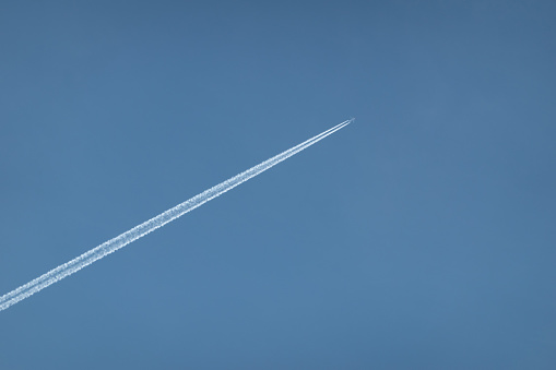 Passenger airplane with vapor trails against a clear blue sky