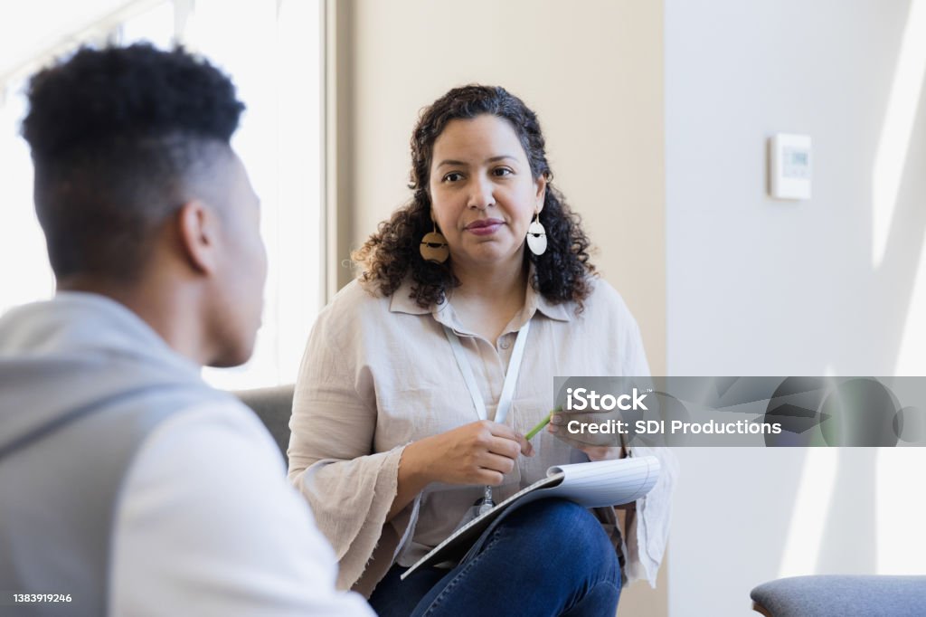Counselor listens The counselor listens to the young adult and takes notes for their next meeting. Mental Health Professional Stock Photo