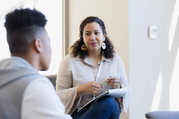 Counselor listens The counselor listens to the young adult and takes notes for their next meeting. psychiatrist stock pictures, royalty-free photos & images