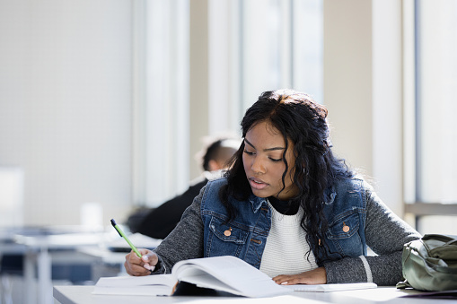 The beautiful young woman concentrates on studying for her upcoming exam.