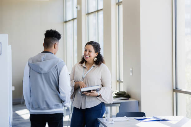 Librarian provides a resource The librarian approaches the young adult man with a resource she found for his research paper. role model stock pictures, royalty-free photos & images