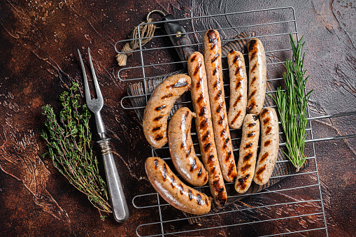 Assortment of different bbq grilled sausages with Beef, pork, lamb and chicken meat on a grill. Dark background. Top view.