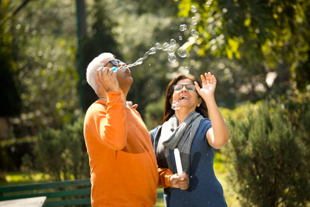 Senior couple blowing bubbles at park