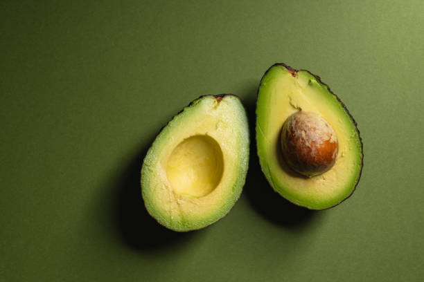 Avocado halves Avocado halves on green background. avocado stock pictures, royalty-free photos & images