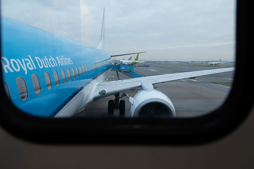 Amsterdam, Netherlands - Dec. 13, 2021: Side view and view of the wing and windows of a KLM, Royal Dutch Airlines aircraft from the access finger