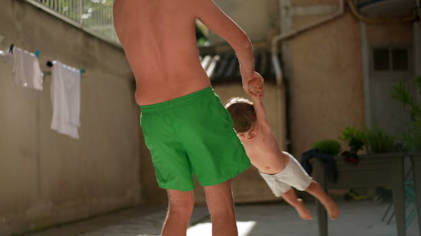istock Father spins son in circles outside 1383933803