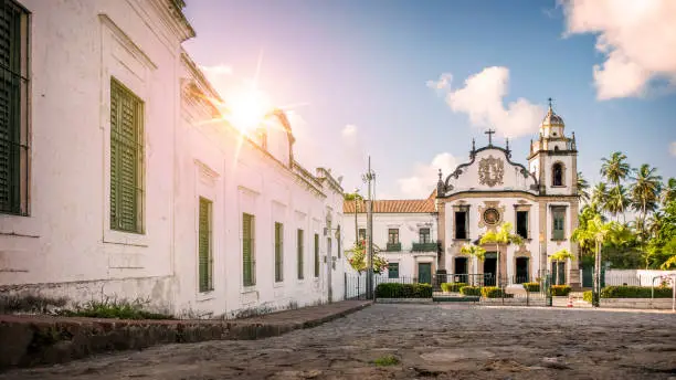 View of the colonial architecture of the Brazilian city of Olinda in Pernambuco, Brazil showcasing its baroque-style buildings dated from the 17th century on elaborated cobblestone street on a sunny tropical day.
