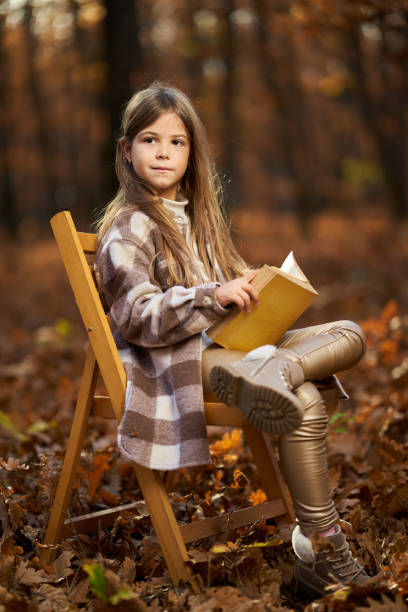 Young caucasian girl reading a book, candid autumnal portrait in the forest stock photo