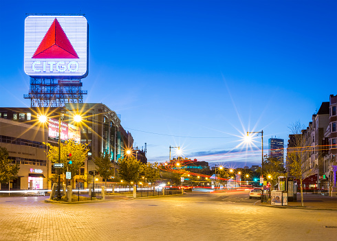Boston, MA, USA - June 25, 2017: view of the architecture of Boston in Massachusetts, USA at night showcasing the Kenmore Square with its famous landmark the CitGo neon sign and red brick pavement by the Fenway Park Stadium.