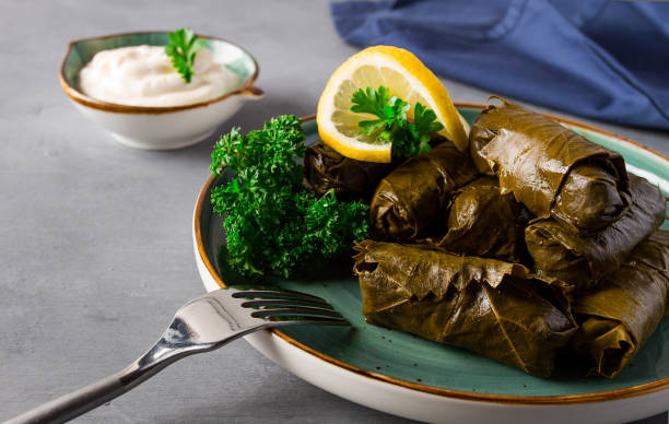 istock Dolma, cabbage rolls, grape leaves with filling, white sauce, lemon and herbs, rustic, selective focus, no people, 1383944074