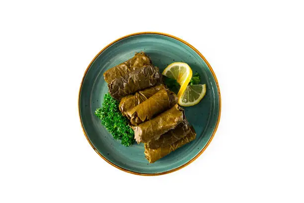 Photo of Dolma, cabbage rolls, grape leaves with filling, lemon and herbs, rustic, selective focus, no people,