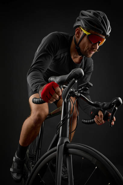 istock male cyclist riding road bicycle on black background 1383946198