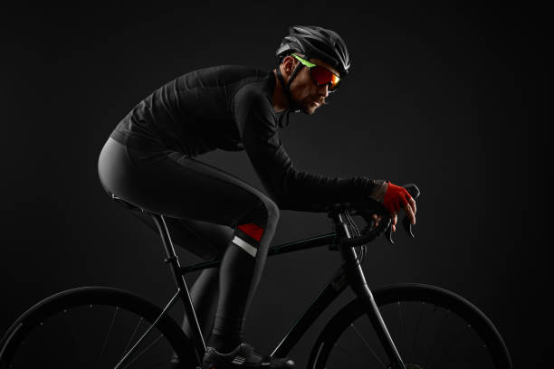 istock male cyclist riding road bicycle on black background 1383947401