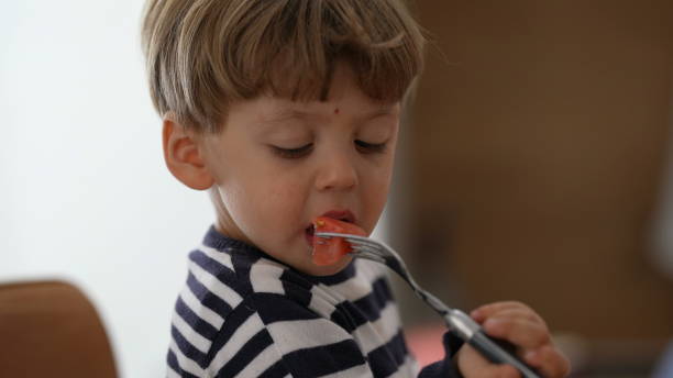istock One child eating fruit snack holding fork by himself 1383952457