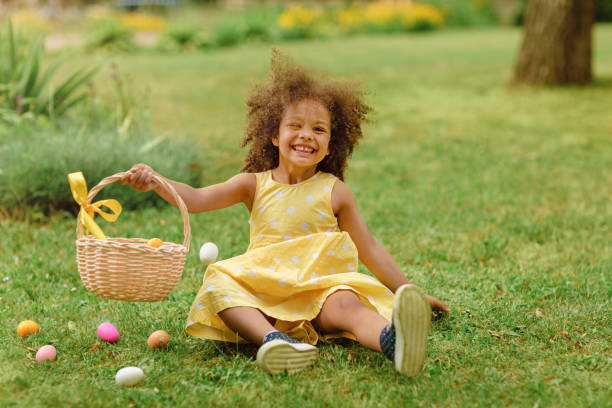 istock Little Black girl wtfring bunny ears gathering Easter eggs 1383952550