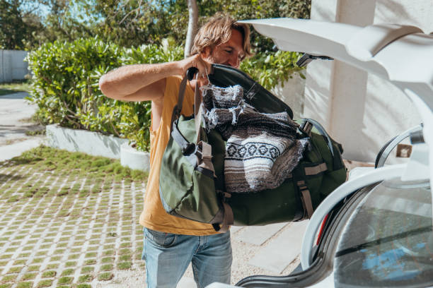 istock Male packing for a trip loading his baggage onto a car trunk 1383952622