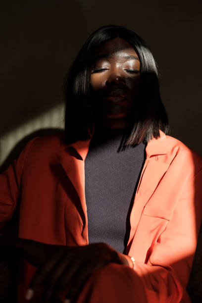 A black woman has her eyes closed in a dark environment.
