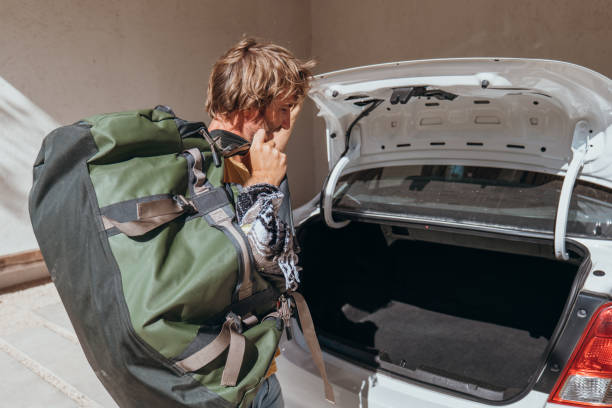 istock Male packing for a trip loading his baggage onto a car trunk 1383953941