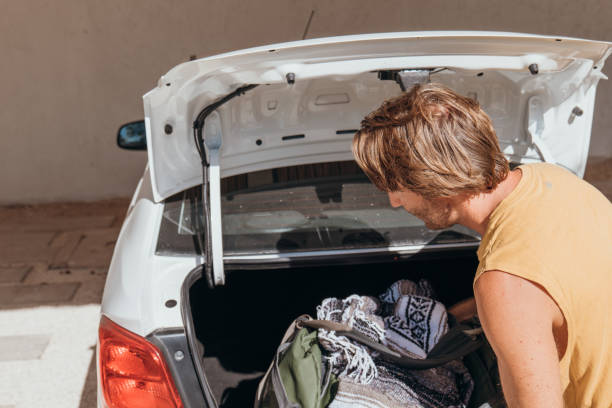 istock Male packing for a trip loading his baggage onto a car trunk 1383955814