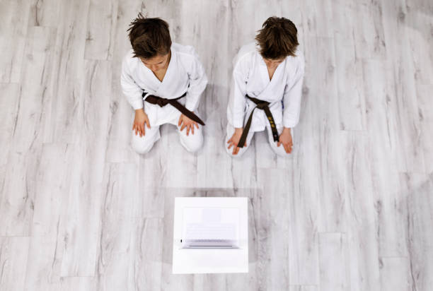 Two teenage boys training karate at home. Modern spacious apartment. They are listening to online karate lesson. Canon R5