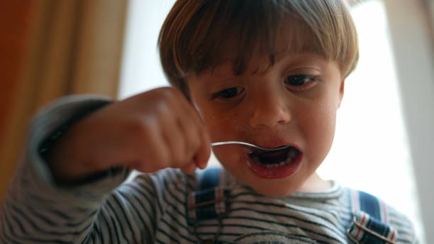 istock Small boy eating yogurt with spoon. Child eating snack 1383960088