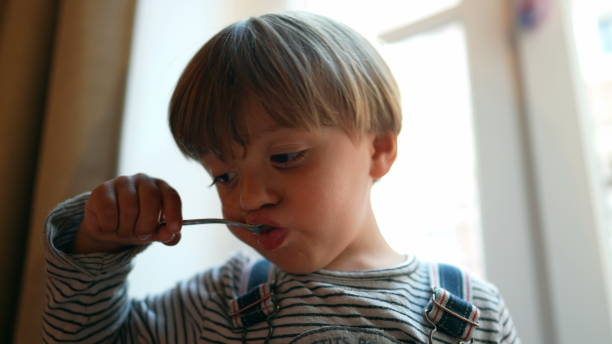 istock Small boy eating yogurt with spoon. Child eating snack 1383960126
