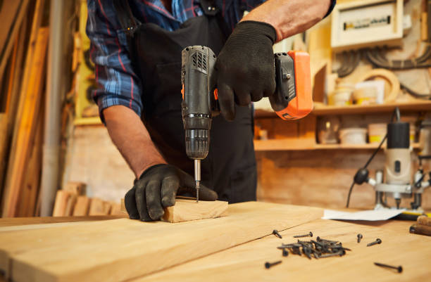istock Senior carpenter with drilling instrument working in the carpentry workshop to make a piece of furniture 1383961417