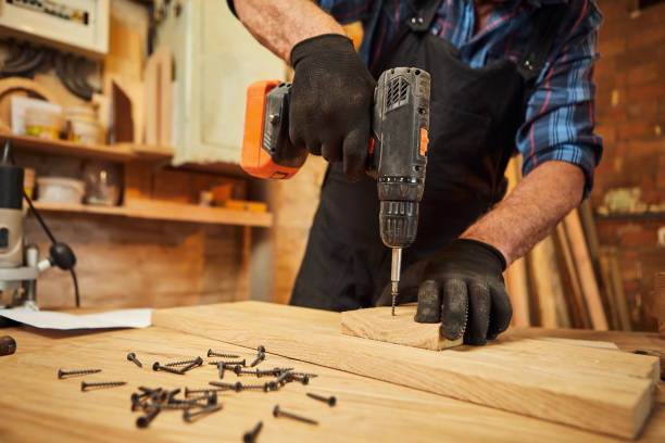 istock Senior carpenter with drilling instrument working in the carpentry workshop to make a piece of furniture 1383961432