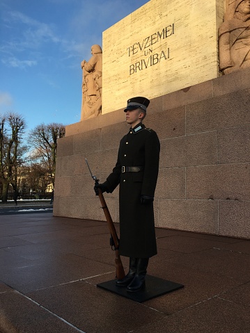 Arlington County, United States – April 21, 2019: A soldier standing at attention and holding a rifle while in a uniform outside of a building