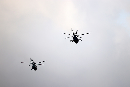 Military helicopters in flight on gray sky background