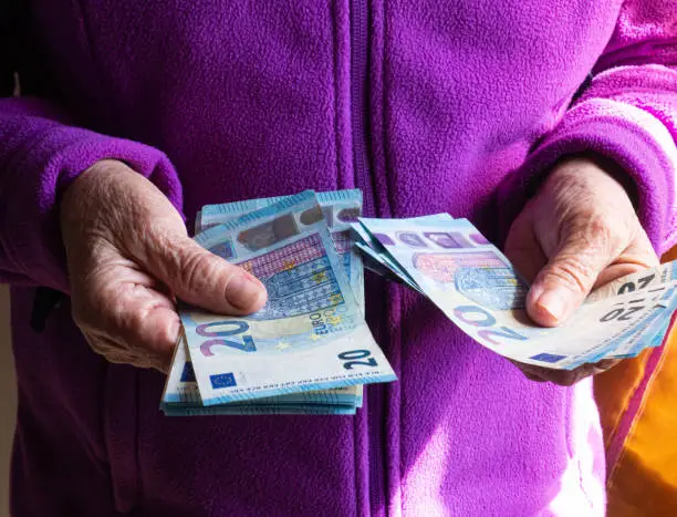 Photo of Woman's hands are holding a few euro coins. Pension, poverty, social problems and the theme of old age. Saving.