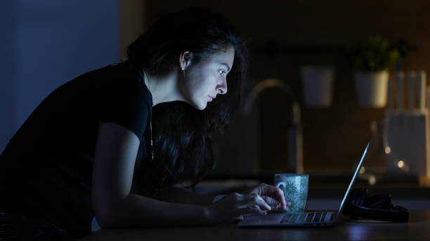 istock Woman browsing internet in front of laptop screen at night 1383962937