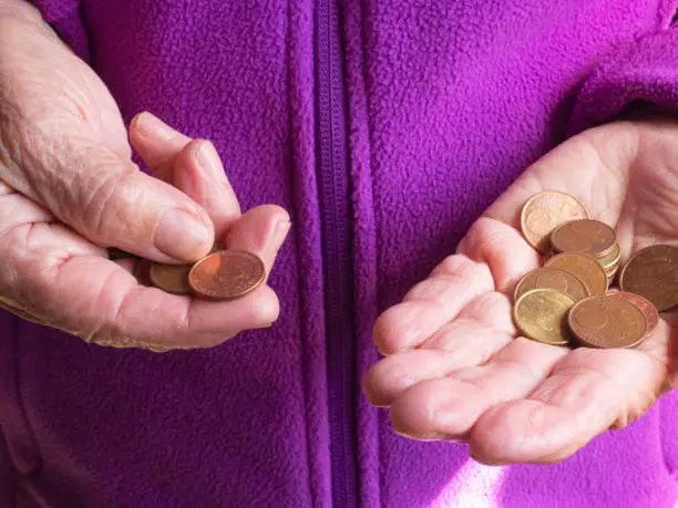 Photo of Woman's hands are holding a few euro coins. Pension, poverty, social problems and the theme of old age. Saving.