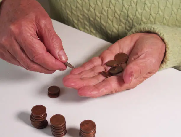 Photo of Woman's hands are holding a few euro coins. Pension, poverty, social problems and the theme of old age. Saving.