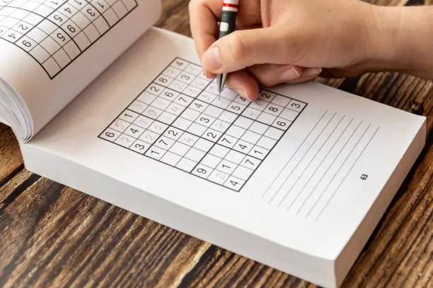 A person solving a sudoku puzzle using a mechanical pencil.