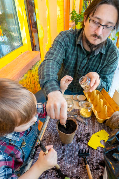 istock father helps his son plant seeds in a peat pot 1383966555