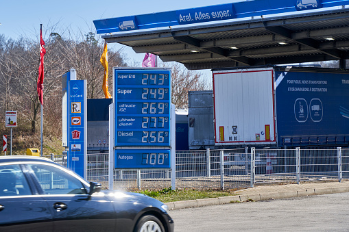 Sindelfingen, Germany - March 10, 2022: Price board with high gasoline, diesel and fuel prices. Most expensive gas and oil prices at German aral filling station in Europe. Car in motion.