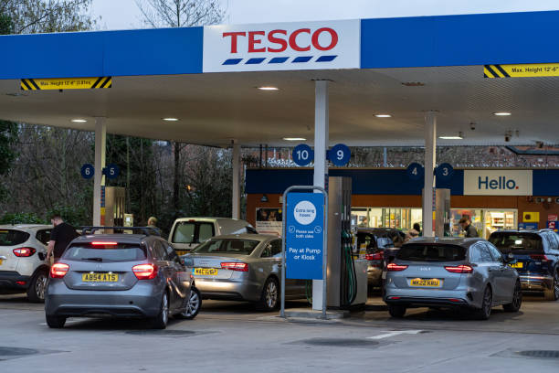 Wigan, UK: March 10, 2022: Queuing cars waiting to buy fuel at a Tesco petrol filling station as British drivers panic buy fuel stock photo
