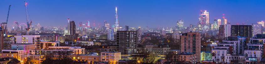 Panoramic aerial view over the landmarks of London glittering before sunrise.