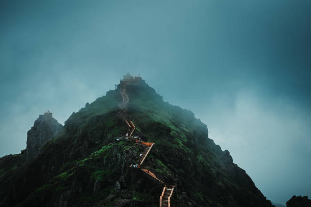 Beautiful view of clouds and fog on top of Girnar hills during monsoon. View of the Dattatreya temple located on the last 10,000th step at Mount Girnar in Junagadh, Gujarat, India Beautiful view of clouds and fog on top of Girnar hills during monsoon. View of the Dattatreya temple located on the last 10,000th step at Mount Girnar in Junagadh, Gujarat, India junagadh stock pictures, royalty-free photos & images