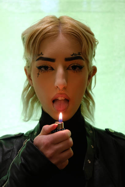 istock Young cyber punk female portrait licking fire from a lighter 1383973470