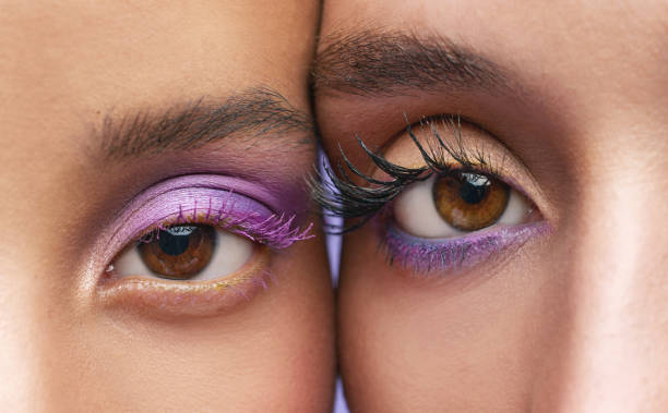 scatto ritagliato di due giovani donne che indossano il trucco viola - trucco per gli occhi foto e immagini stock