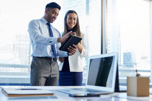 Shot of two businesspeople discussing something on a digital tablet This is some impressive stuff colleague stock pictures, royalty-free photos & images