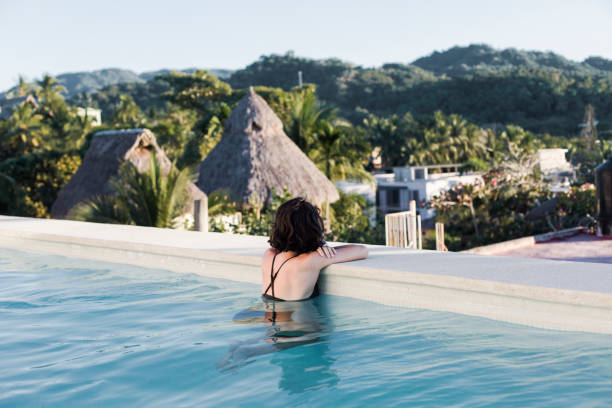 istock Young woman in a swimming pool with a view 1383977402