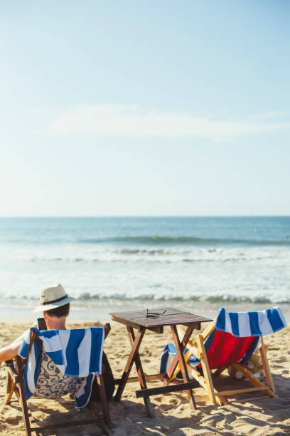 ビーチで読書をする成熟した男 - reading beach e reader men ストックフォトと画像